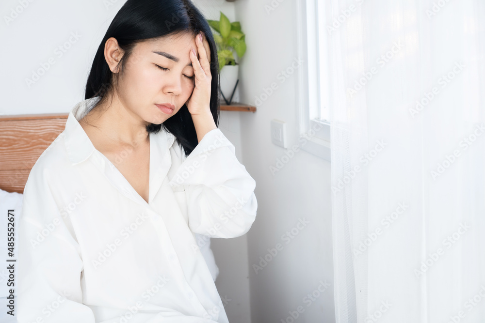 Asian woman suffering from headache, dizziness after wakeup in morning hand holding her head Asian woman suffering from headache, dizziness after wakeup in morning hand holding her head