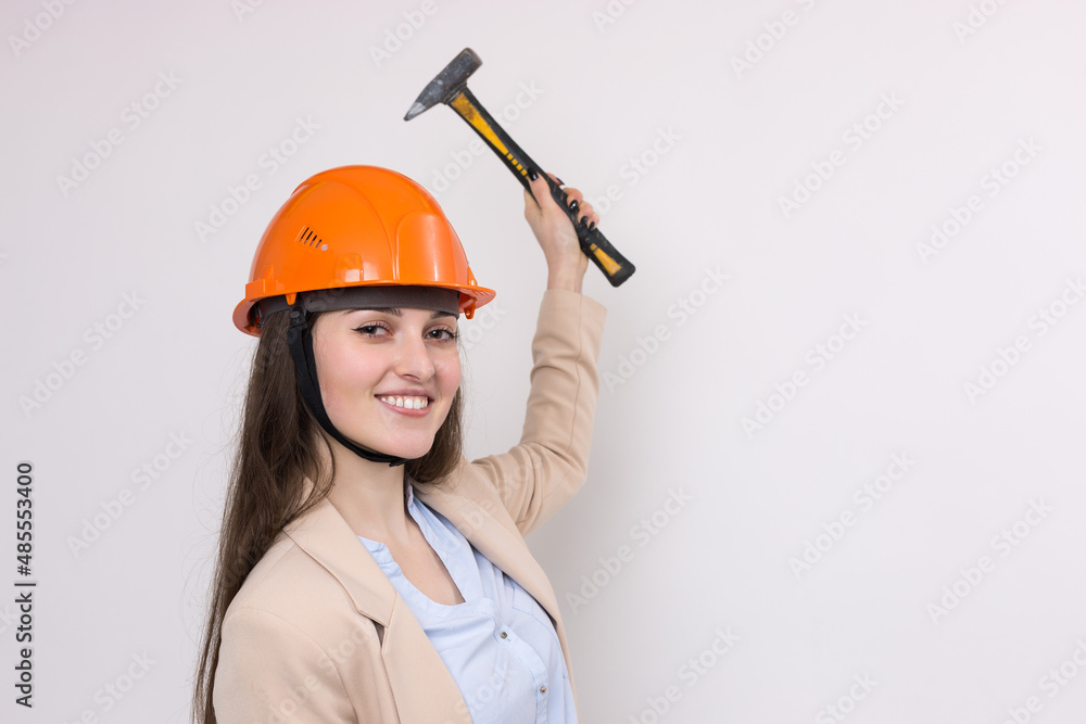 Girl engineer in an orange construction helmet with a hammer on a white background. Girl engineer in an orange construction helmet with a hammer on a white background.