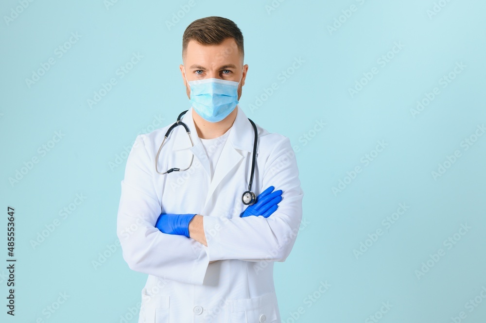 Man in medical gloves putting on protective face mask against blue background Man in medical gloves putting on protective face mask against blue background
