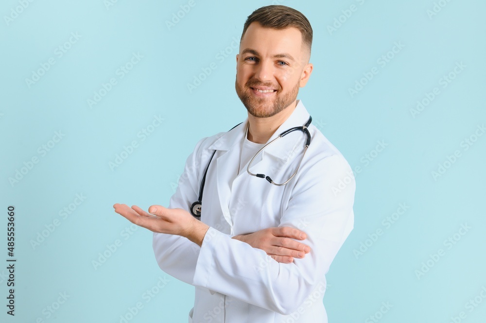 Horizontal banner of smiling young male doctor showing and presenting something with hand, isolated on blue background with copy space on the left side Horizontal banner of smiling young male doctor showing and presenting something with hand, isolated on blue background with copy space on the left side