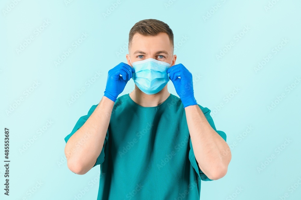 Handsome male doctor in medical uniform put on protective mask against covid-19 virus. Coronavirus protection, healthcare, medical equipment Handsome male doctor in medical uniform put on protective mask against covid-19 virus. Coronavirus protection, healthcare, medical equipment