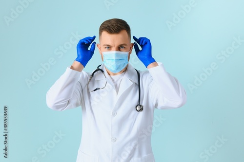 Male doctor in medical mask on color background © Serhii