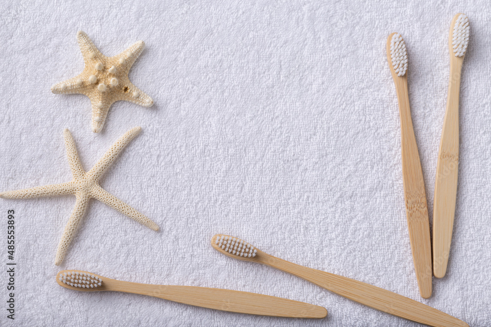 A set of eco-friendly bamboo wooden toothbrushes with starfish on a white towel. A set of eco-friendly bamboo wooden toothbrushes with starfish on a white towel.