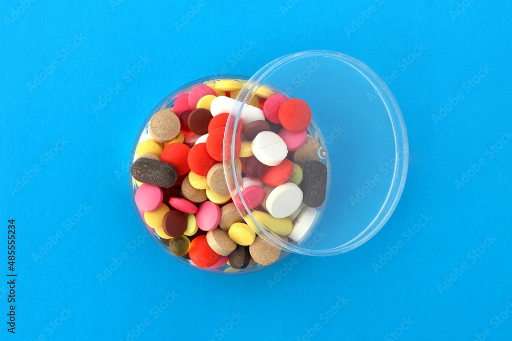 There are many multi-colored pills on a transparent bowl.