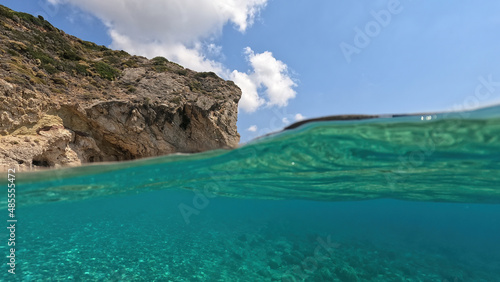 Fototapeta Naklejka Na Ścianę i Meble -  Underwater split photo of natural exotic island rocky bay with turquoise crystal clear sea and small caves