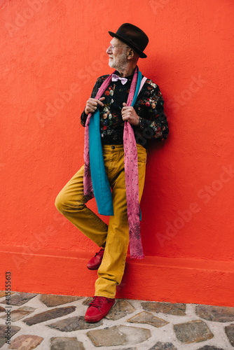 Senior man looking away thoughtfully against a red wall © Jacob Lund
