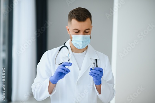 A doctor in blue gloves holding a bottle with vaccine. Close up shot. Medicine and healthcare concept