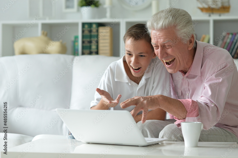 Boy and grandfather with a laptop at home