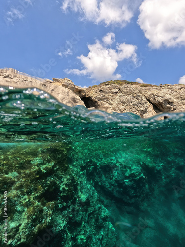 Underwater split photo of beautiful paradise pebble rocky bay of Kaladi with turquoise crystal clear sea and small caves, Kythira island, Ionian, Greece