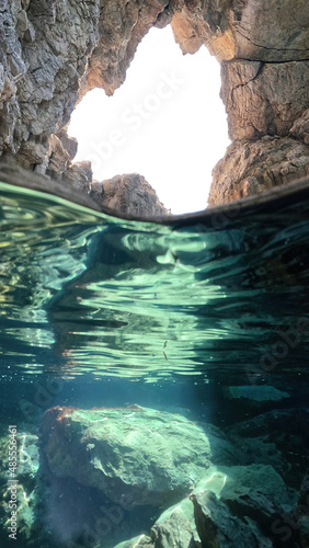 Underwater split photo of beautiful paradise pebble rocky bay of Kaladi with turquoise crystal clear sea and small caves, Kythira island, Ionian, Greece © aerial-drone