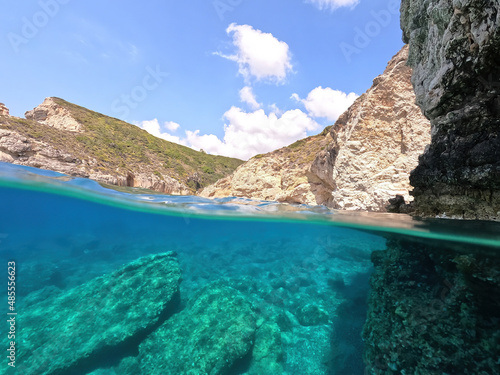 Underwater split photo of beautiful paradise pebble rocky bay of Kaladi with turquoise crystal clear sea and small caves, Kythira island, Ionian, Greece
