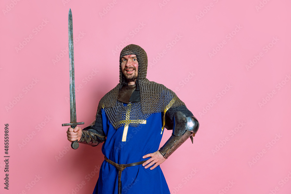 Fototapeta premium Half-length portrait of man, medieval warrior or knight with wounded face posing isolated over pink studio background