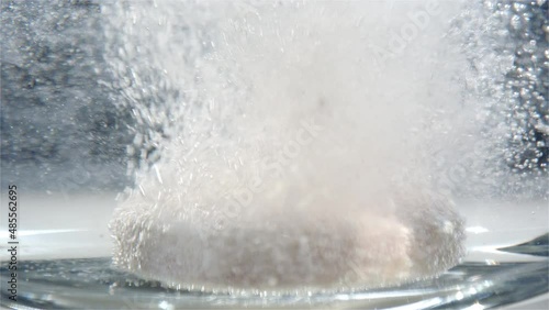 STATIC, MACRO - An effervescent tablet drops into a glass of water photo