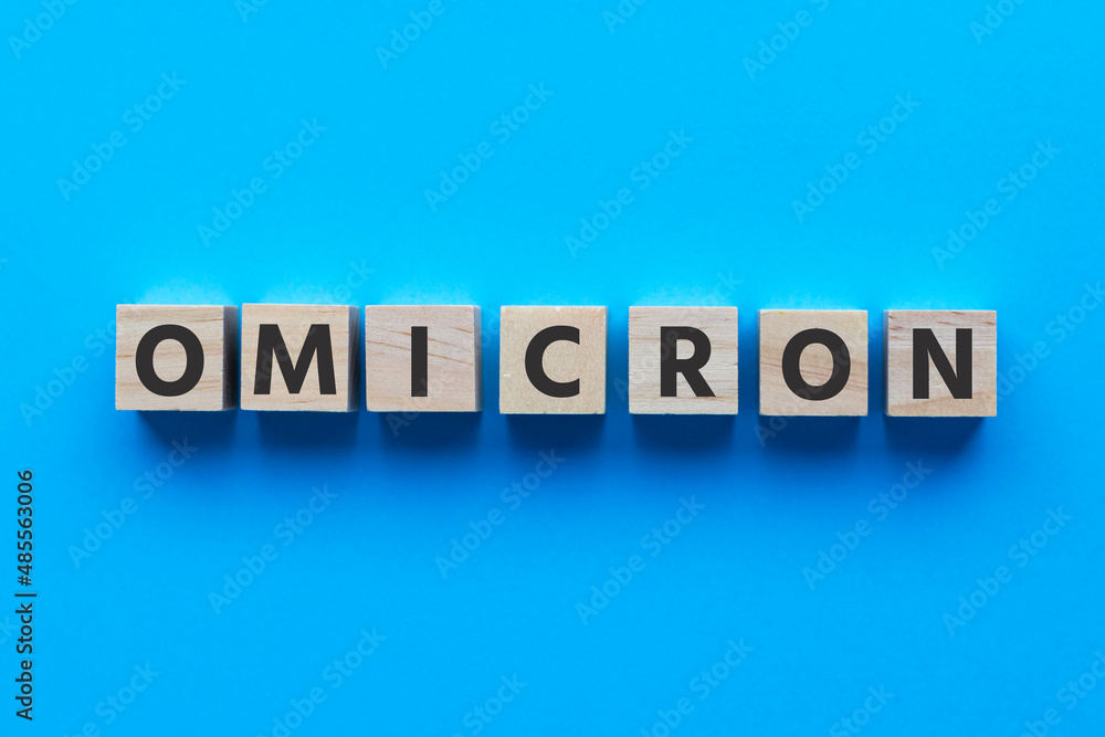 Text OMICRON on wooden cubes on bright blue background. Medicine and healthcare concept. Text OMICRON on wooden cubes on bright blue background. Medicine and healthcare concept.