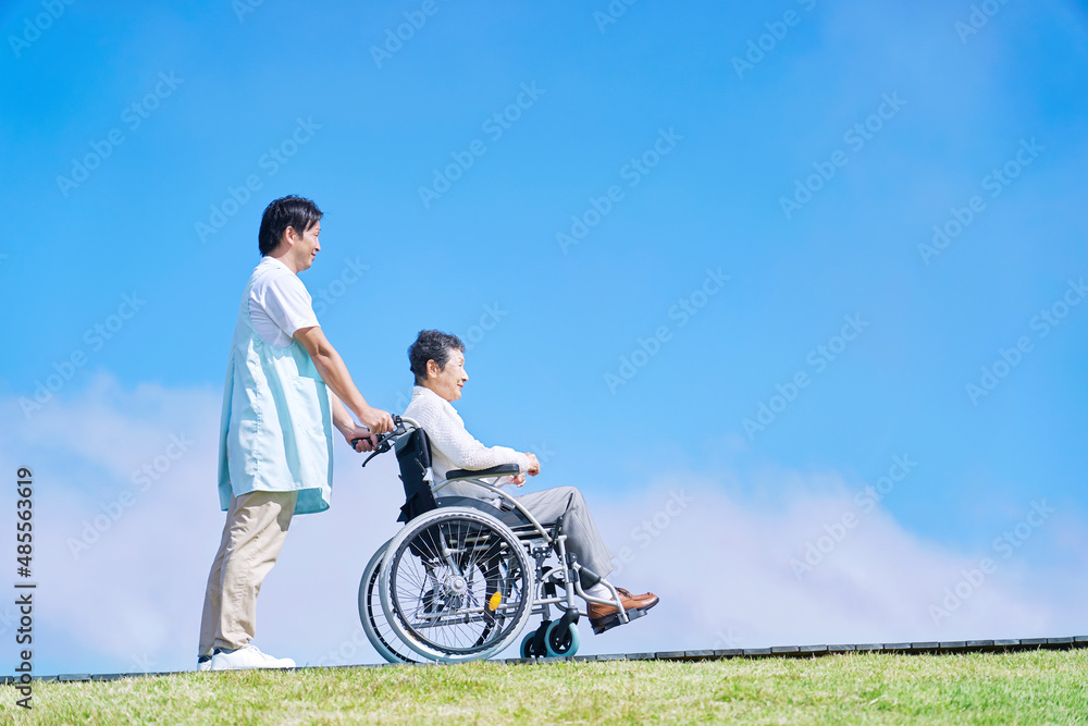 Obraz premium 介護士と車椅子に乗る高齢者 屋外