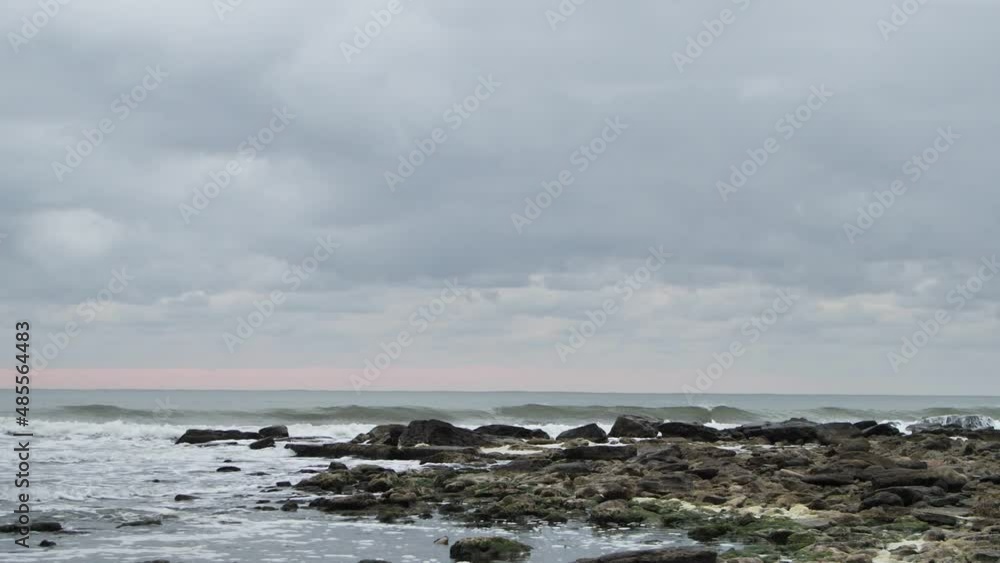 Waves breaking on rocks on sunset in slow motion. Strong waves breaking on mossy rocks at sunset with pink sky in slow motion Waves breaking on rocks on sunset in slow motion. Strong waves breaking on mossy rocks at sunset with pink sky in slow motion
