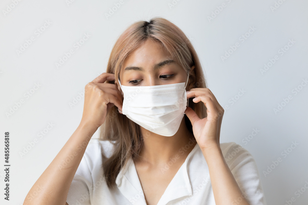 Serious woman wearing white mask for seasonal flu and dust pollution protection Serious woman wearing white mask for seasonal flu and dust pollution protection