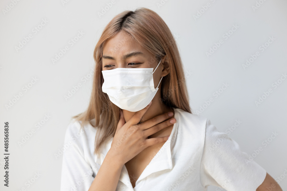 Sick young woman with face mask having sore throat, acute pharyngitis, tonsillitis, tonsils inflammation, air pollution allergy Sick young woman with face mask having sore throat, acute pharyngitis, tonsillitis, tonsils inflammation, air pollution allergy