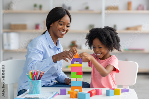 Vászonkép Adorable black kid and child development specialist playing with bricks