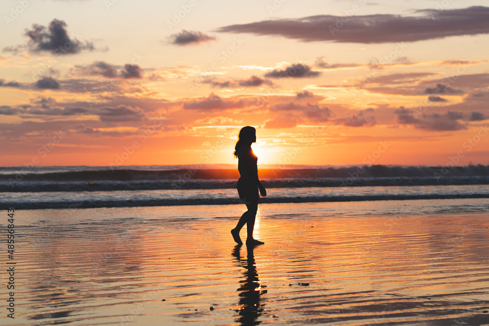 Woman walking on the beach at a beautiful sunset in Costa Rica