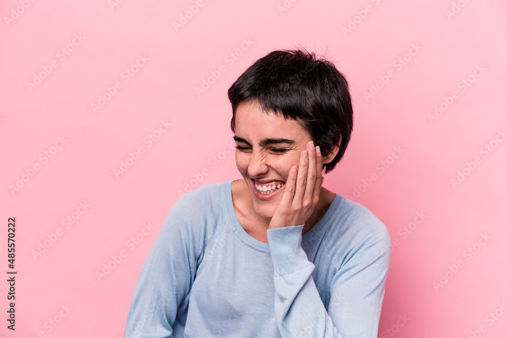 Young caucasian woman isolated on pink background laughs happily and has fun keeping hands on stomach.