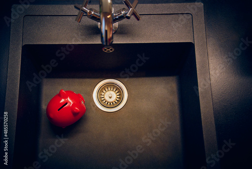 Red piggy bank, money, dark gray shell, silver modern faucet in the background