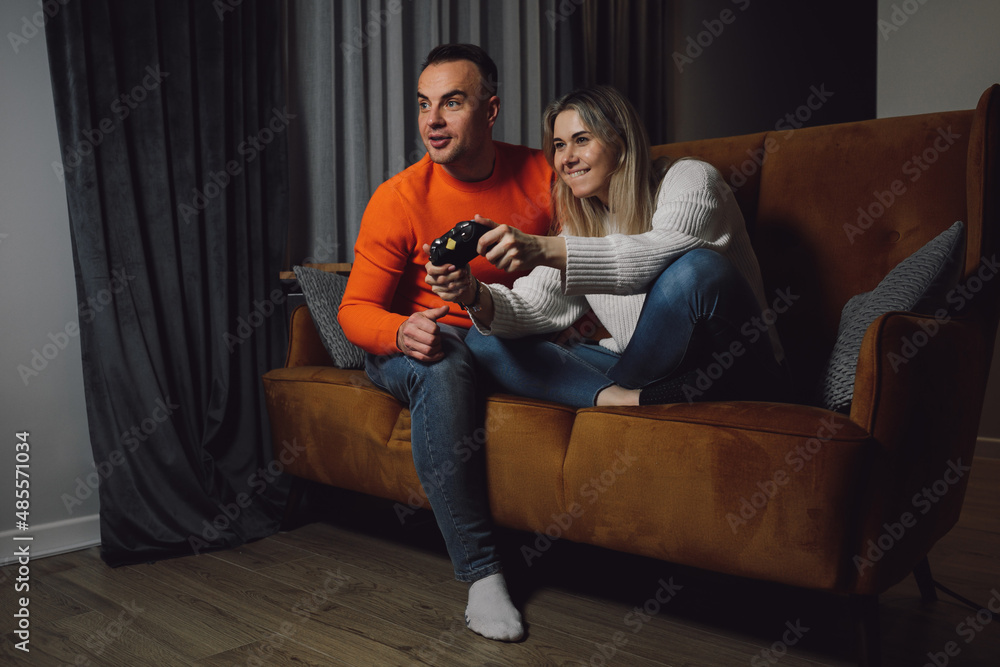 young cheerful family playing games with joystick on comfortable brown sofa. Looking at TV and rejoice in victory. young cheerful family playing games with joystick on comfortable brown sofa. Looking at TV and rejoice in victory.