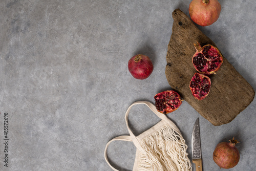 Wallpaper Mural Beautiful red pomegranate fruit composition on a concrete background. Half pomegranate and ripe pomegranate fruit with rustic wooden board, knife and string bag. Top view. Torontodigital.ca
