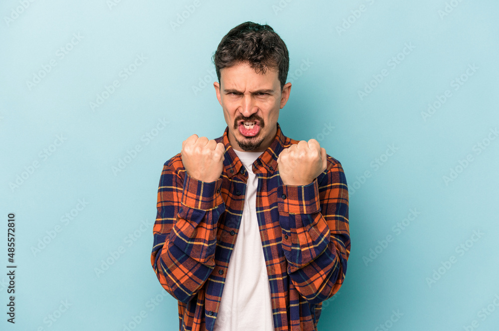 Young caucasian man isolated on blue background upset screaming with tense hands.