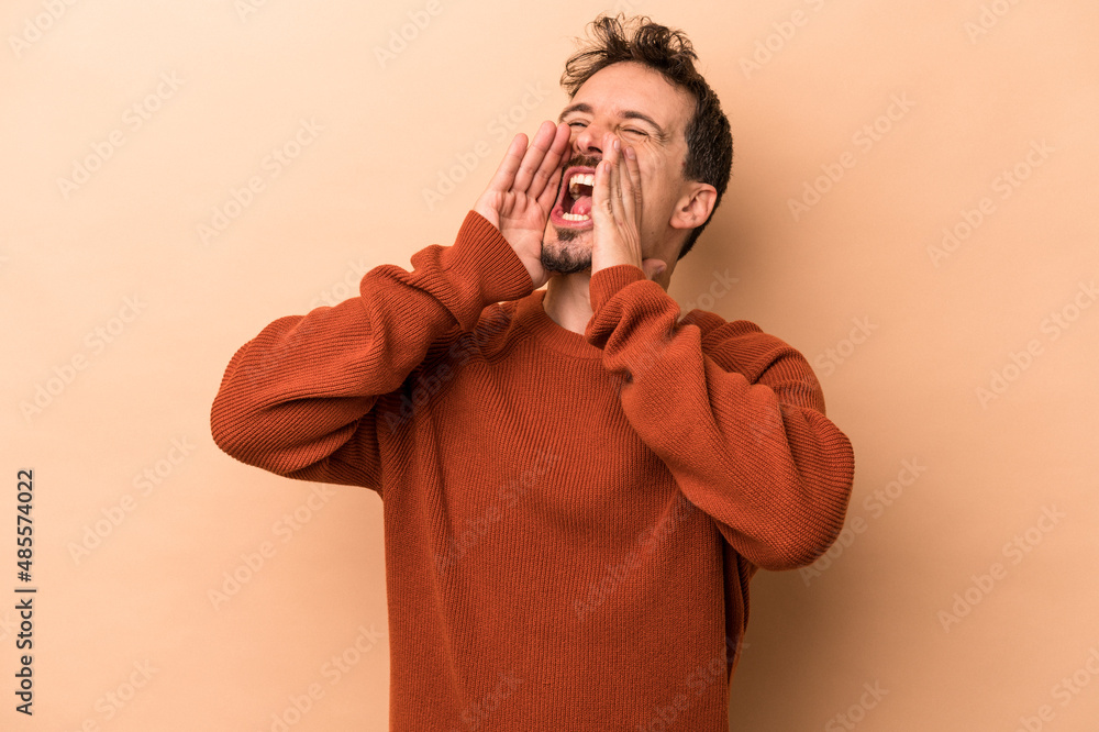 Young caucasian man isolated on beige background shouting excited to front. Young caucasian man isolated on beige background shouting excited to front.