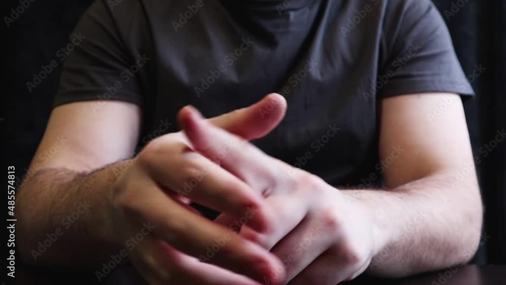 A man breaks his knuckles and fingers. Cracking knuckles on the table. Close up of man's hand with gray background A man breaks his knuckles and fingers. Cracking knuckles on the table. Close up of man's hand with gray background