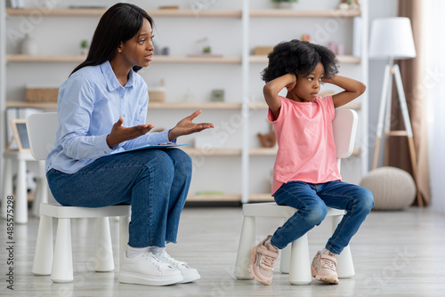 African american woman psychotherapist talking to unruly little girl
