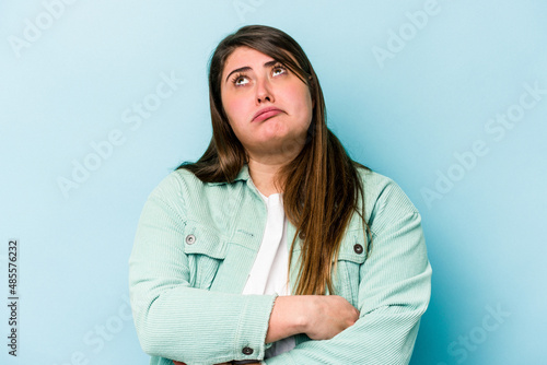 Young caucasian overweight woman isolated on blue background tired of a repetitive task.