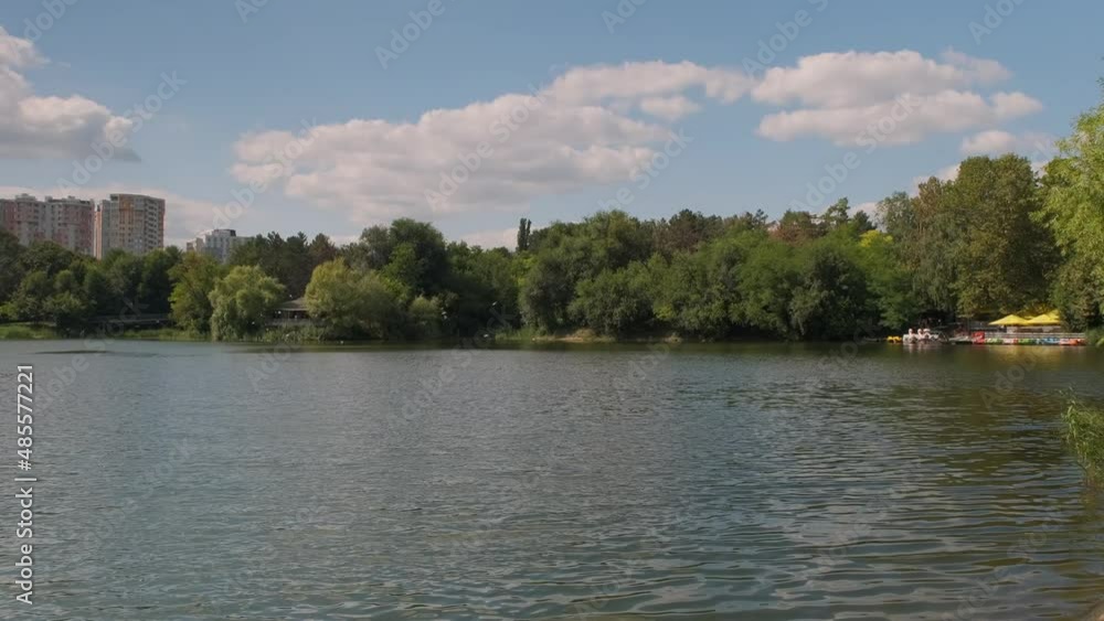 Pond with green water among lawns and trees against buildings of city. Pond with green water among lawns and trees against buildings of city.