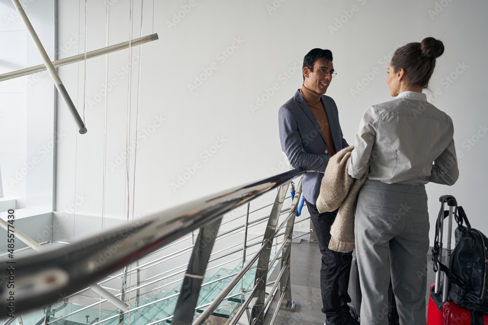 Smiling gentleman having conversation with lady with luggage Smiling gentleman having conversation with lady with luggage