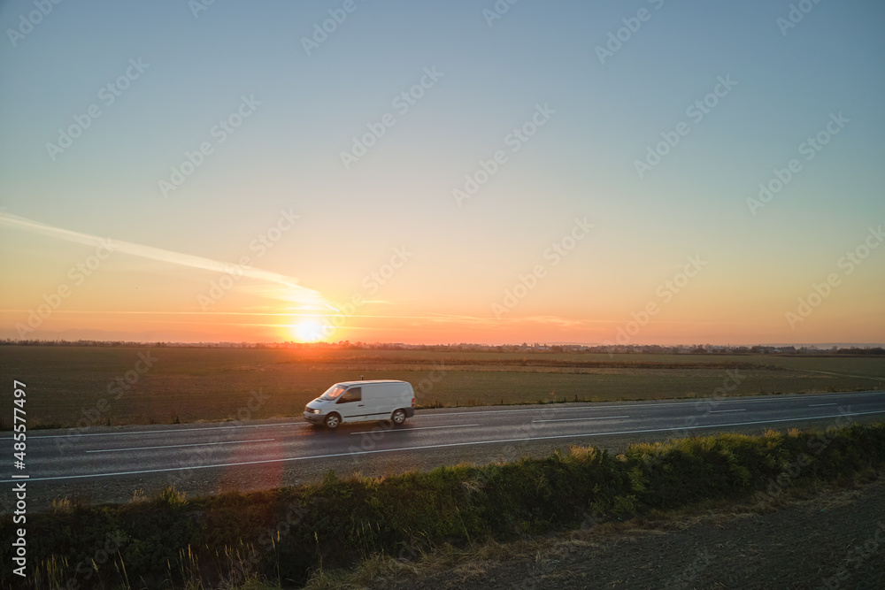 Fototapeta premium Aerial view of intercity road with blurred fast driving car at sunset. Top view from drone of highway traffic in evening