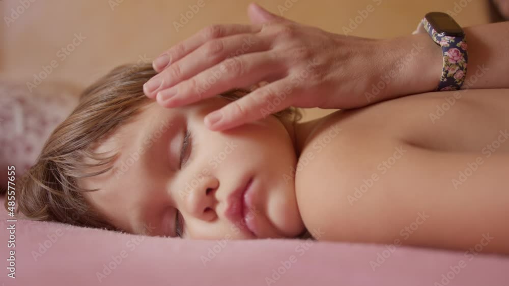 Close-up of the face of a little girl sleeping in bed, mom gently touches her hair Close-up of the face of a little girl sleeping in bed, mom gently touches her hair