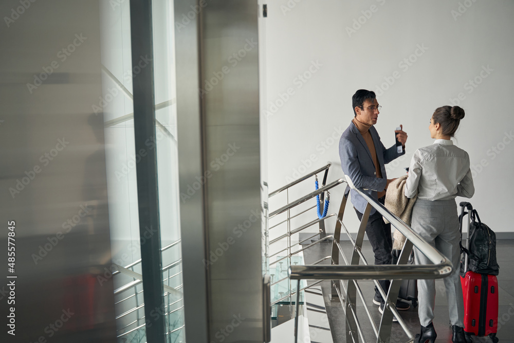 Male with travel documents talking to female in corridor