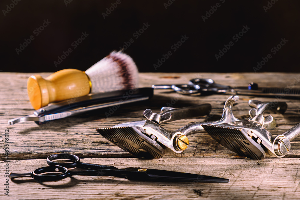 On a rustic wooden weathered surface are old barber tools. Vintage manual hair clipper comb razor shaving brush shaving brush hairdressing scissors. horizontal. On a rustic wooden weathered surface are old barber tools. Vintage manual hair clipper comb razor shaving brush shaving brush hairdressing scissors. horizontal.