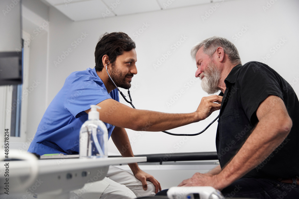 Male doctor examining senior patient with stethoscope Male doctor examining senior patient with stethoscope