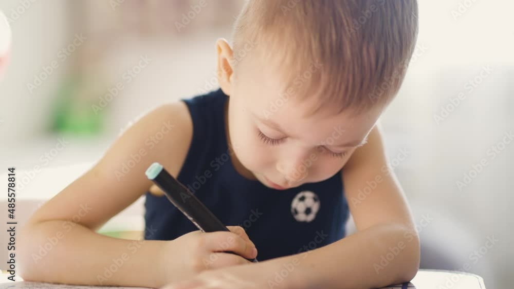 Drawing. Little boy with pencil coloring at home. Child draws at the table. Psychology of the child's personality. Help gaining confidence. Creativity and education concept. Drawing. Little boy with pencil coloring at home. Child draws at the table. Psychology of the child's personality. Help gaining confidence. Creativity and education concept.