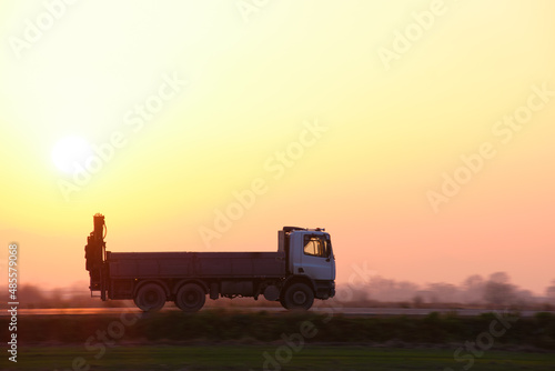 Canvastavla Cargo dump truck driving on highway hauling goods in evening
