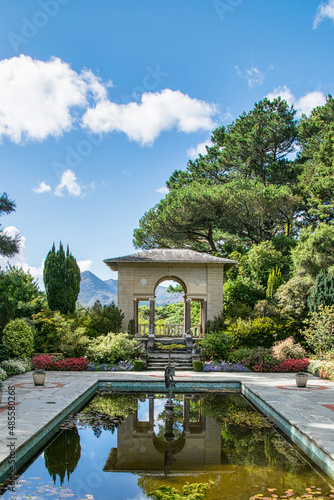 Ein wunderschön angelegter Garten mit einem Torbogen und einem Teich, der die Szenerie spiegelt photo