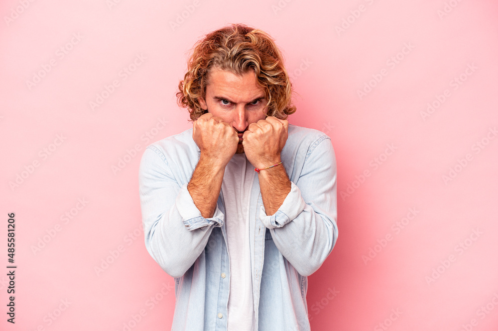 Young caucasian man isolated on pink background throwing a punch, anger, fighting due to an argument, boxing. Young caucasian man isolated on pink background throwing a punch, anger, fighting due to an argument, boxing.