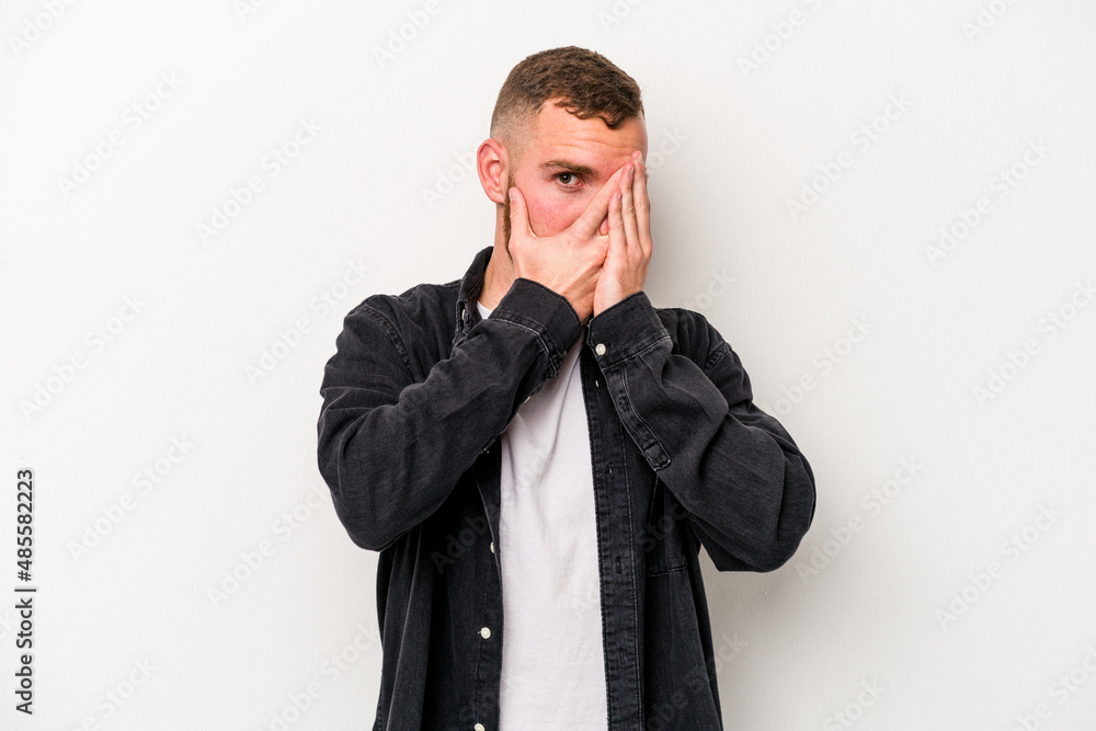 Young caucasian man isolated on white background blink through fingers frightened and nervous. Young caucasian man isolated on white background blink through fingers frightened and nervous.