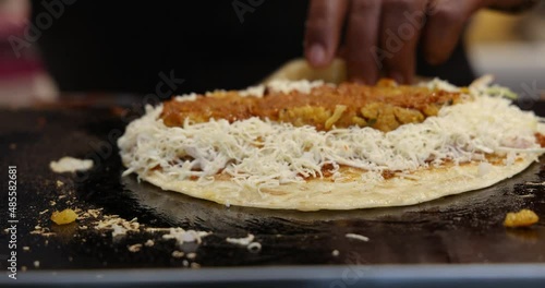 A Chef making Vegetable Frankie, Kathi Roll, Veg Franky Wrap. Adding Sauces, Potato Filling, spices to Cabbage Salad on a Indian Refined Flour Flat bread. Mumbai, Maharashtra, India. 4811. photo