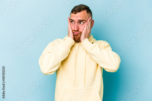 Young caucasian man isolated on blue background scared and afraid.