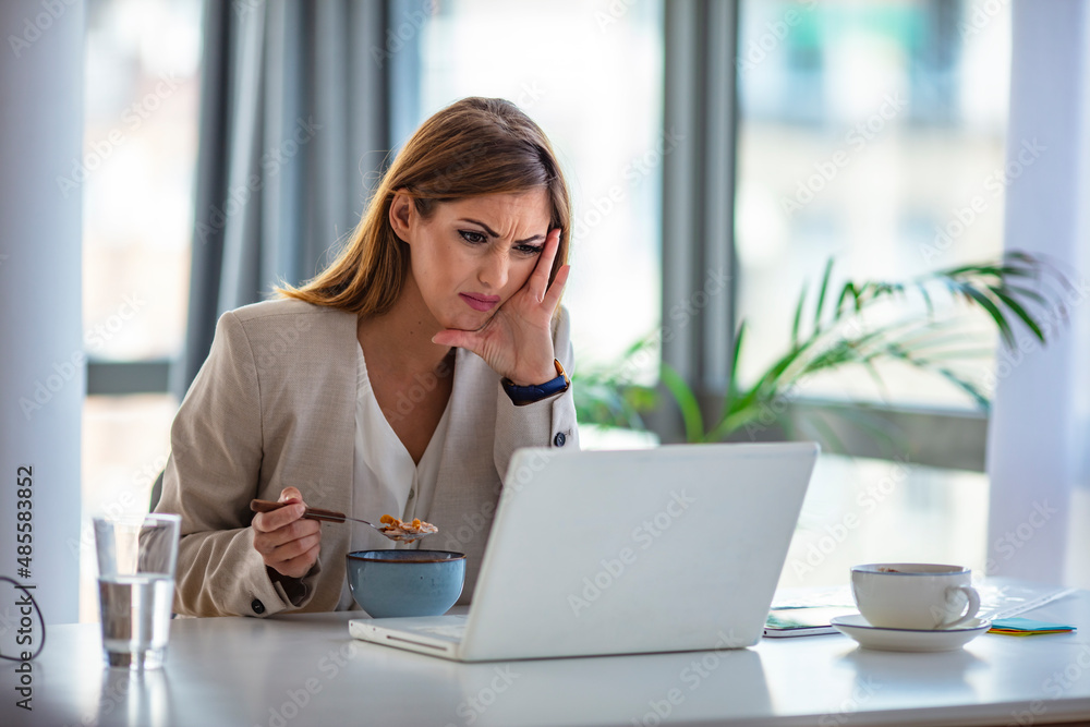 A woman in the office eats at work. Laptop at the table. She is at her workplace. , a glass of water and coffee in the background. The concept of lunch at work and healthy food. A woman in the office eats at work. Laptop at the table. She is at her workplace. , a glass of water and coffee in the background. The concept of lunch at work and healthy food.
