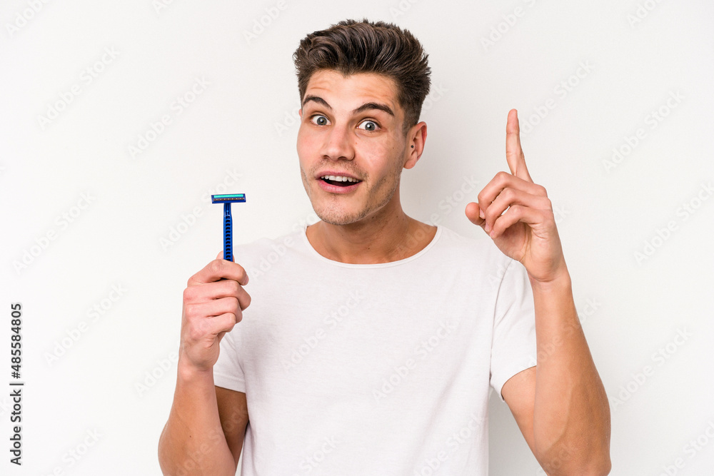 Young caucasian man shaving his beard isolated on white background having an idea, inspiration concept. Young caucasian man shaving his beard isolated on white background having an idea, inspiration concept.