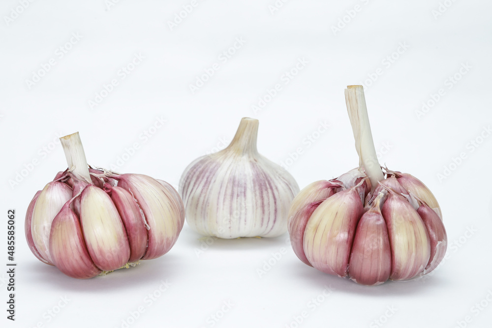 Obraz premium Three heads of garlic (Allium sativum), with their units still in the bulb, one with the peel and two without, on a neutral background